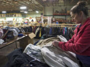 Cheryl Payne, a volunteer staff member with Friends of the Carpenter, sorts donated coats and jackets that were collected by local Boy Scouts.