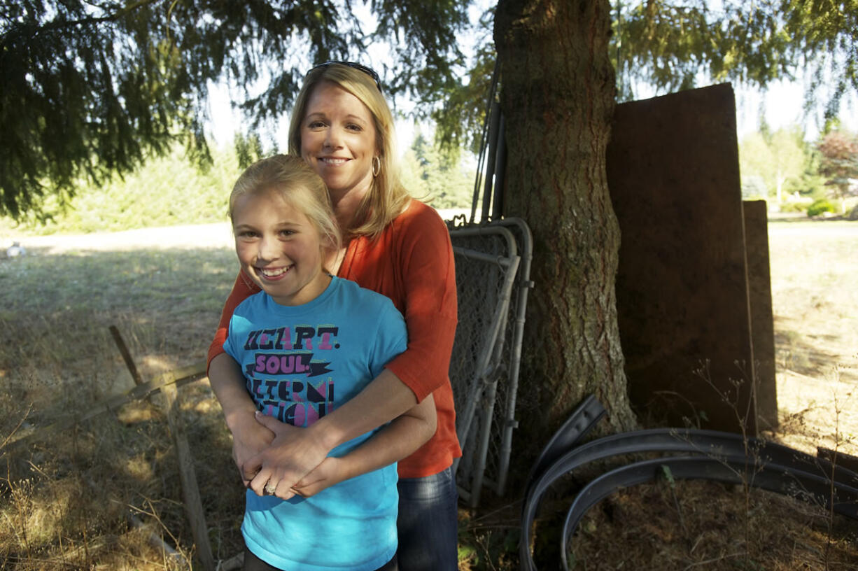 Paityn Mock, 10, and her mother, Jenn Mock, stand by the tree Paityn hid behind when burglars broke into their house in October.