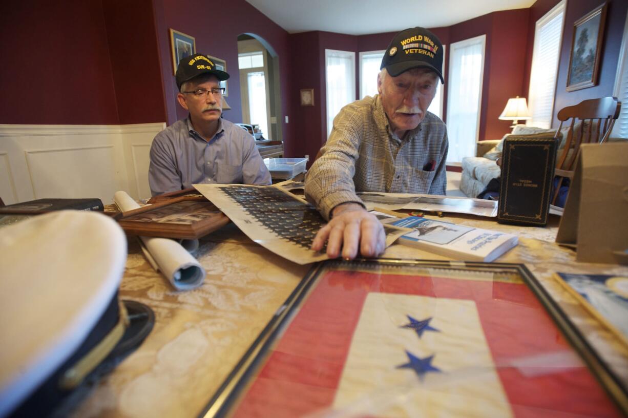 Keith Cupp, left, and dad Ted Cupp look over keepsakes from their service on the two USS Enterprise aircraft carriers. The two blue stars on the flag showed that Ted Cupp's family had two sons serving in World War II. Both brothers were at Iwo Jima, Ted said.