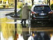 A motorist gets his feet wet Tuesday as he braves a new body of water on West Sixth Street in Vancouver.