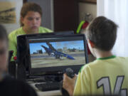 Children play on computer flight simulators at Pearson Field Education Center's Open Cockpit Day on Saturday.