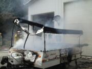 Firefighters spray down a pop-up camping trailer that caught fire at a residence in Ridgefield.