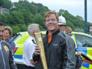 Drew Colburn holds the Olympic torch on the Isle of Man in June.