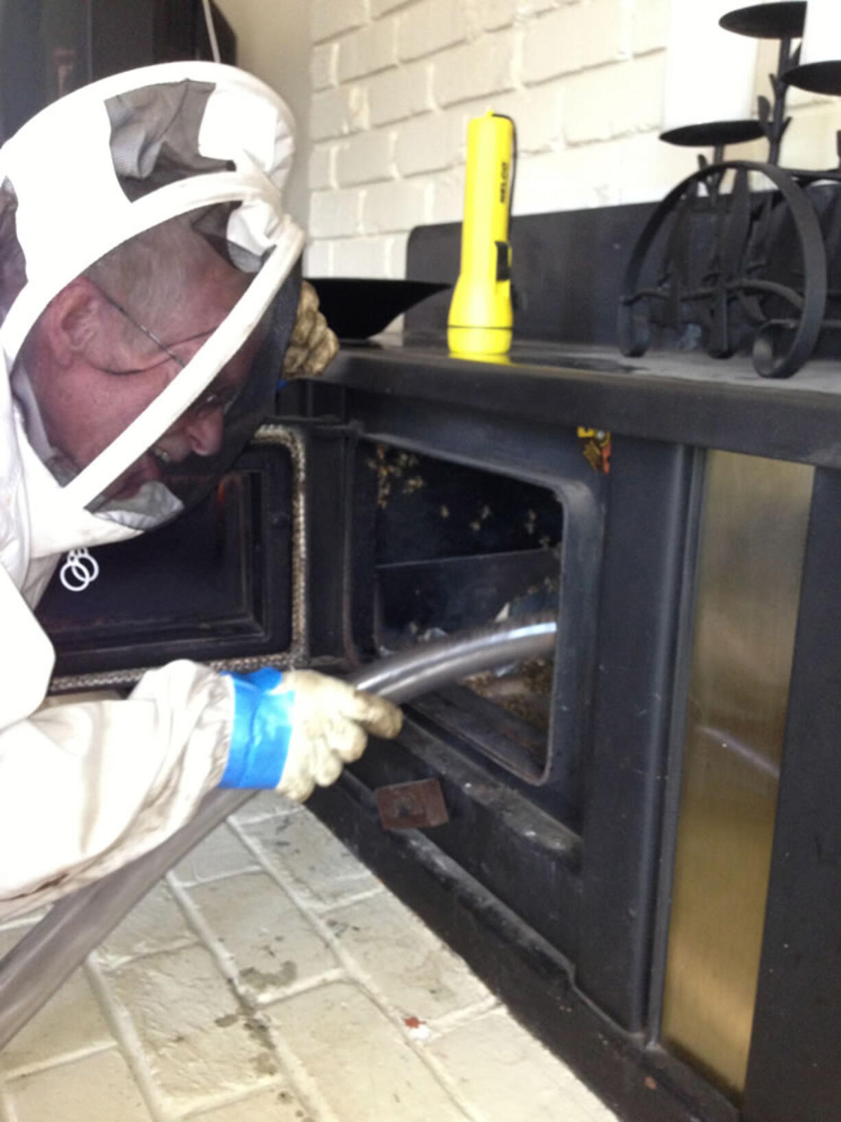 Clark County Beekeepers Association volunteer Ron Prindle, 63, uses a homemade vacuum contraption last weekend to suck thousands of honeybees that had swarmed into a chimney at Anne Hargreaves' Washougal home.