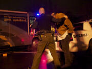 Deputy Chris Luque of the Clark County Sheriff's Office leads a suspected drunken driver into WSP's mobile Impaired Driving Unit during the annual Night of 1,000 Stars DUI crackdown in early December. The name is meant to evoke police badges shining in the night.