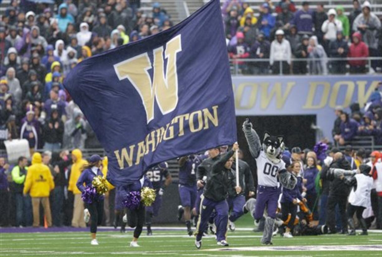 The University of Washington football team runs onto the field at Husky Stadium before its game Saturday against Arizona.