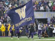 The University of Washington football team runs onto the field at Husky Stadium before its game Saturday against Arizona.