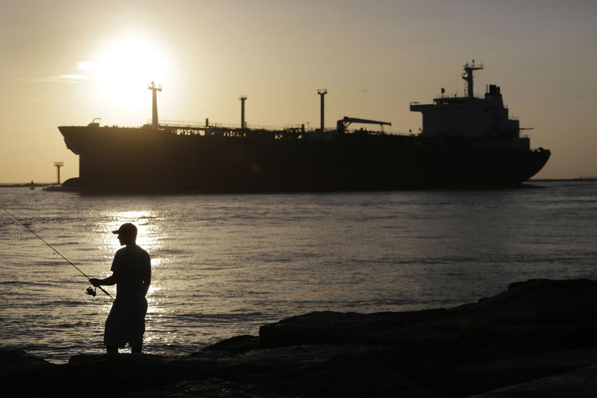 An oil tanker passes a fisherman as it enters a channel near Port Aransas, Texas, heading for the Port of Corpus Christi.