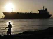 An oil tanker passes a fisherman as it enters a channel near Port Aransas, Texas, heading for the Port of Corpus Christi.