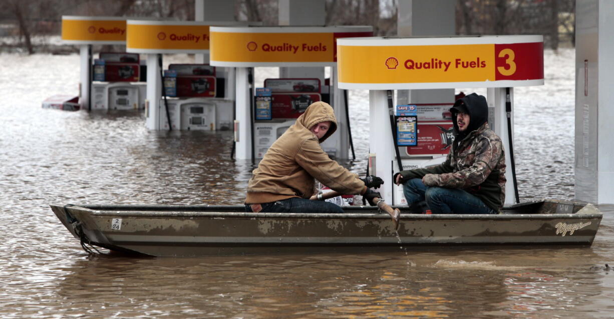 Paul Dusablon, left, and Richard Kotva row from the Circle K at Springdale Park after helping the owner move electronics off the floor inside the convenience store, in Fenton, Mo., Wednesday, Dec. 30, 2015. A rare winter flood threatened nearly two dozen federal levees in Missouri and Illinois as rivers rose, prompting evacuations in several places. (ROBERT COHEN/St.