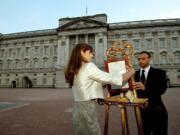 The Queen's Press Secretary, Ailsa Anderson, and Badar Azim, a footman, place an official document to announce the birth of a baby boy to William and Kate, the Duke and Duchess of Cambridge, in the forecourt of Buckingham Palace in London on Monday.