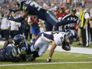 Denver Broncos wide receiver Wes Welker scores a touchdown under the defense of a leaping Seattle Seahawks cornerback Brandon Browner (39) and tackles by Seahawks' Earl Thomas (29) and Antoine Winfield (obscured) in the first half of a preseason NFL football game, Saturday, Aug. 17, 2013, in Seattle.