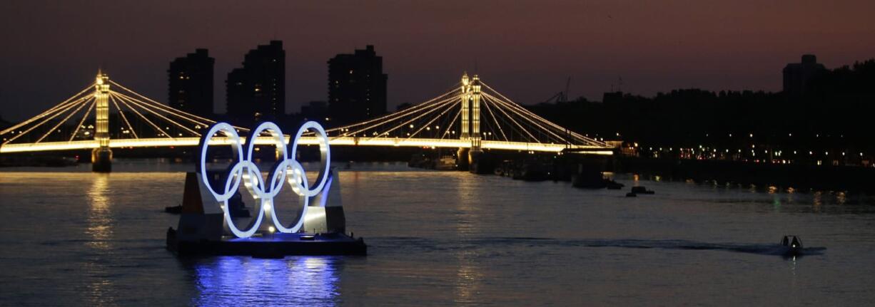 A boat passes a set of Olympic rings floating in the River Thames off of Battersea park Tuesday in London.