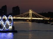 A boat passes a set of Olympic rings floating in the River Thames off of Battersea park Tuesday in London.