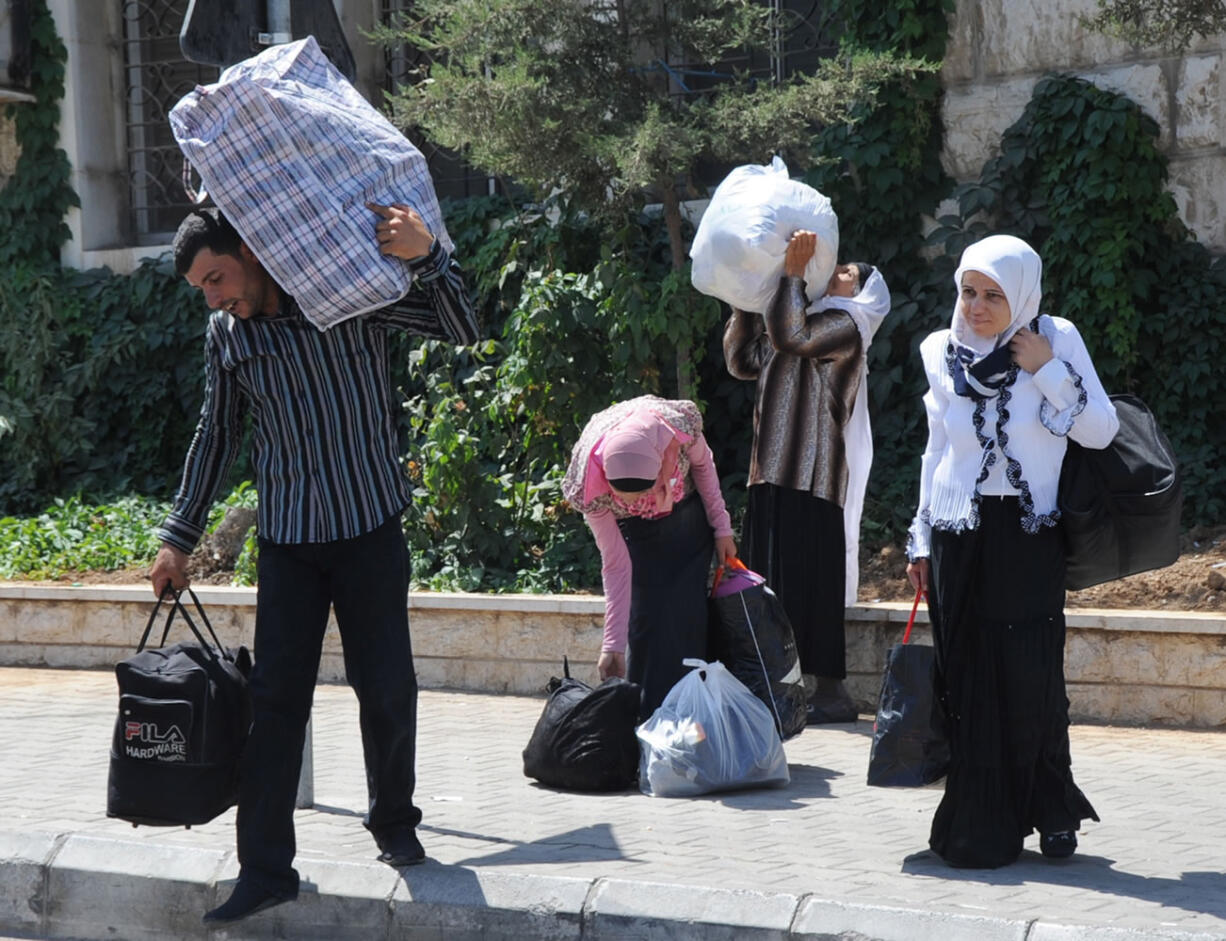 Syrians carry their belongings as they cross into Lebanon at Masnaa, eastern Lebanon, about 25 miles from the Syrian capital of Damascus.