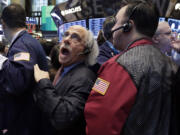 Trader Peter Tuchman, center, works Friday on the floor of the New York Stock Exchange.