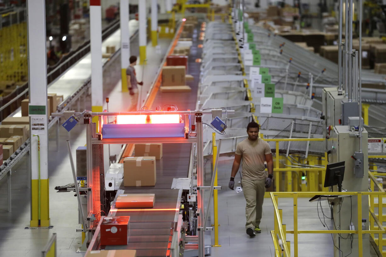 A worker walks near a high-speed scanning conveyor belt, in an area at Amazon.com&#039;s fulfillment center in DuPont.