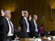 Apple CEO Tim Cook, center, flanked by Peter Oppenheimer, Apple's chief financial officer, left, and Phillip A.