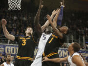 Washington's Aziz N'Diaye (5) tries to block a shot by Arizona State's Jahii Carson (1) as Arizona State's Eric Jacobsen (3) helps defend during the second half Saturday.