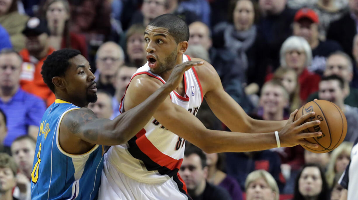 Portland Trail Blazers forward Nicolas Batum, right, from France, looks for help as New Orleans Hornet guard Roger Mason Jr., defends during the first quarter of an NBA basketball game in Portland on  Dec.