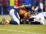 Denver Broncos outside linebacker DeMarcus Ware, right, lies on his fumble recovery for the win after an NFL football game against the Cincinnati Bengals, Monday, Dec. 28, 2015, in Denver. The Broncos won 20-17 in overtime. At left is Denver Broncos inside linebacker Danny Trevathan.