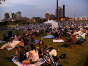 People sit on a hillside during a performance by the Alabama Symphony Orchestra in Railroad Park in Birmingham, Ala.