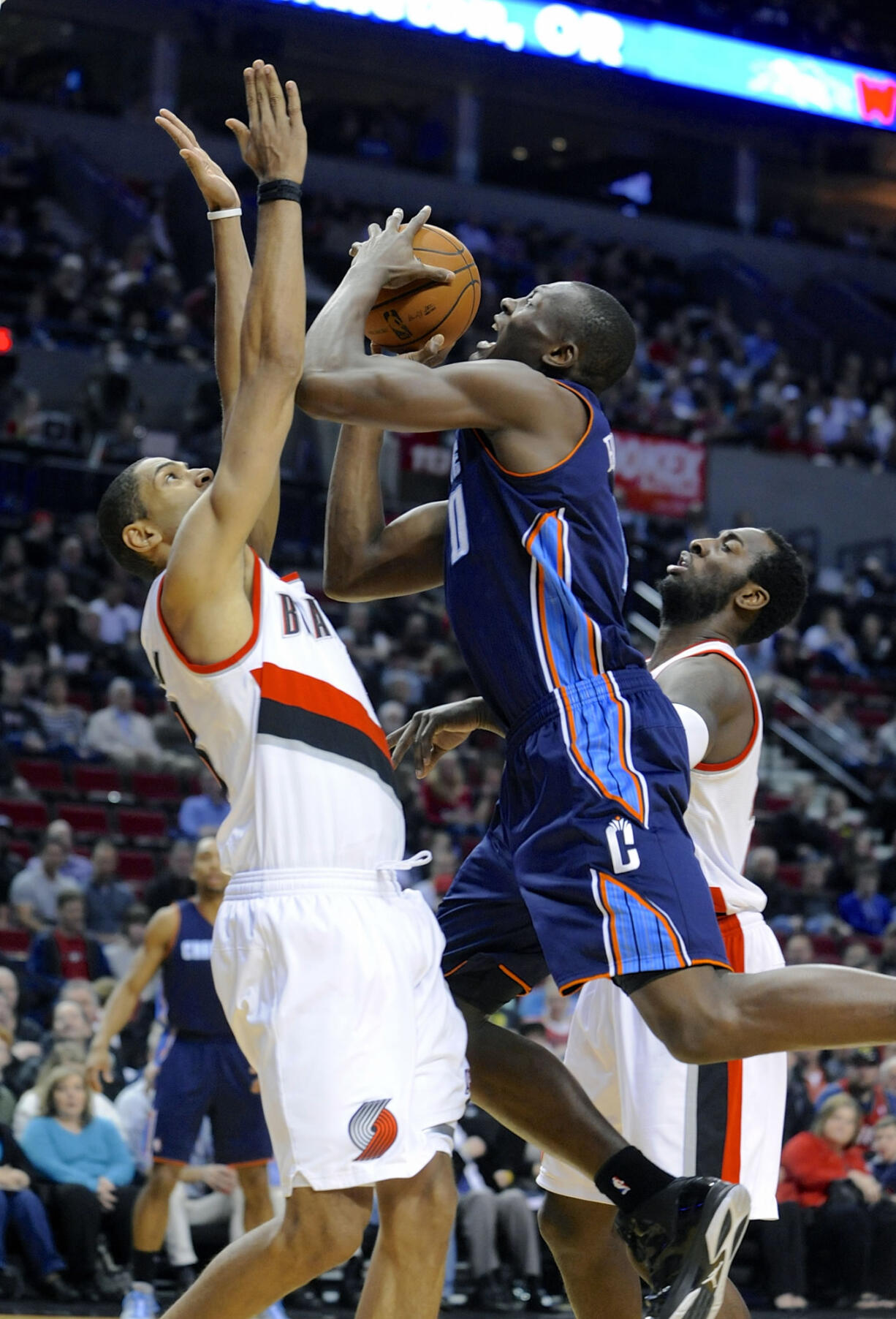 Charlotte's Bismack Biyombo (0) shoots against Portland's Nicolas Batum, left, and JJ Hickson during the first half Monday.