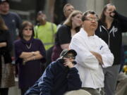 People gather near 13th and J streets to watch firefighters as they recover the body a man hanging from a rope tied to a balcony.