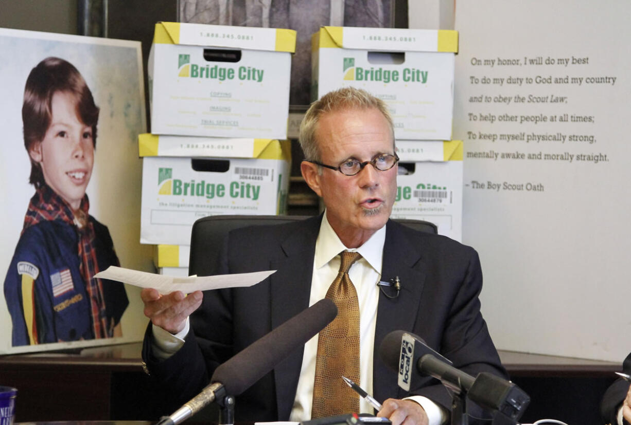 Attorney Kelly Clark speaks in front of former court case illustrations and boxes full of records from the Boy Scouts of America in Portland on June 14.