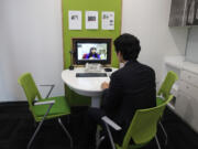 Customer Chung Yong-min does her banking through a screen monitor connected to a video conference with bank employee Oh Ji-young, located in another office, at a Smart Banking Center in Seoul, South Korea.