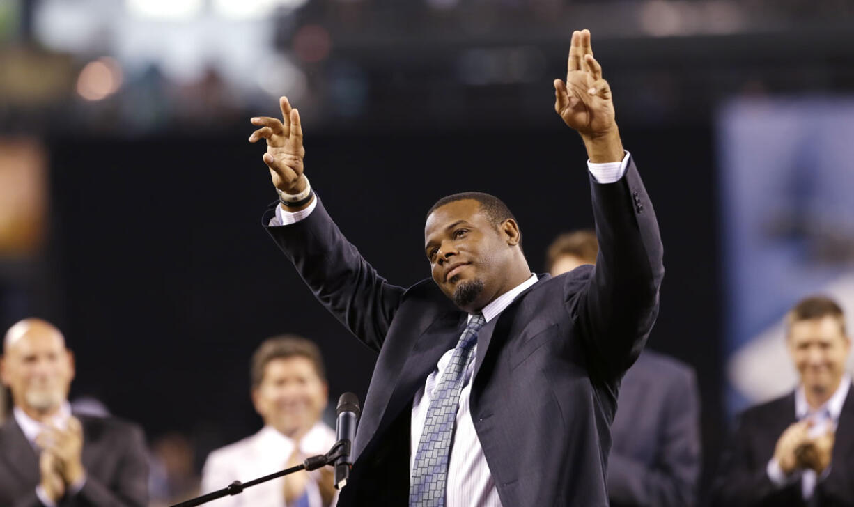 Former Seattle Mariners outfielder Ken Griffey Jr., center, waves to fans as he steps up to speak during a pregame ceremony to induct him into the team's Hall of Fame, Saturday, Aug. 10, 2013, in Seattle. Applauding behind him are former teammates Jay Buhner, left, Edgar Martinez and Dan Wilson.