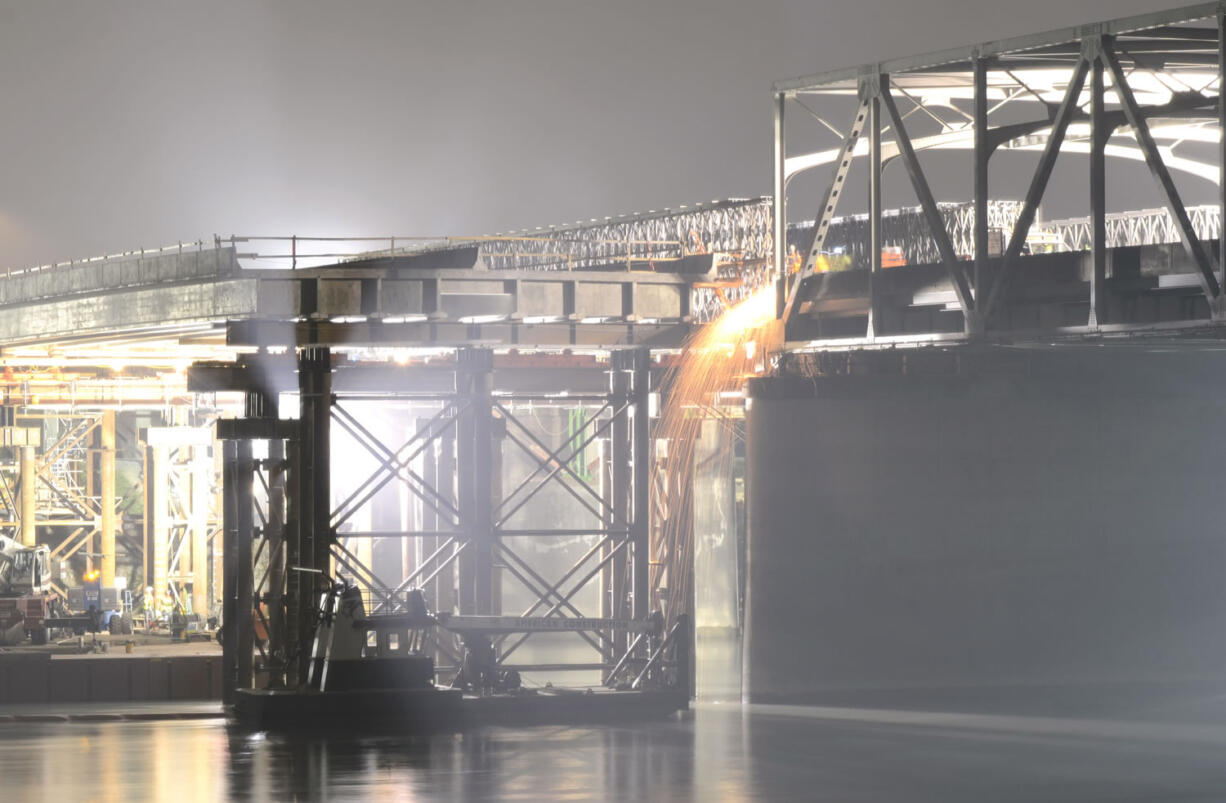 Workers send orange sparks flying as they cut away the anchor bolts to the temporary span Saturday night  on the I-5 Bridge over the Skagit River.