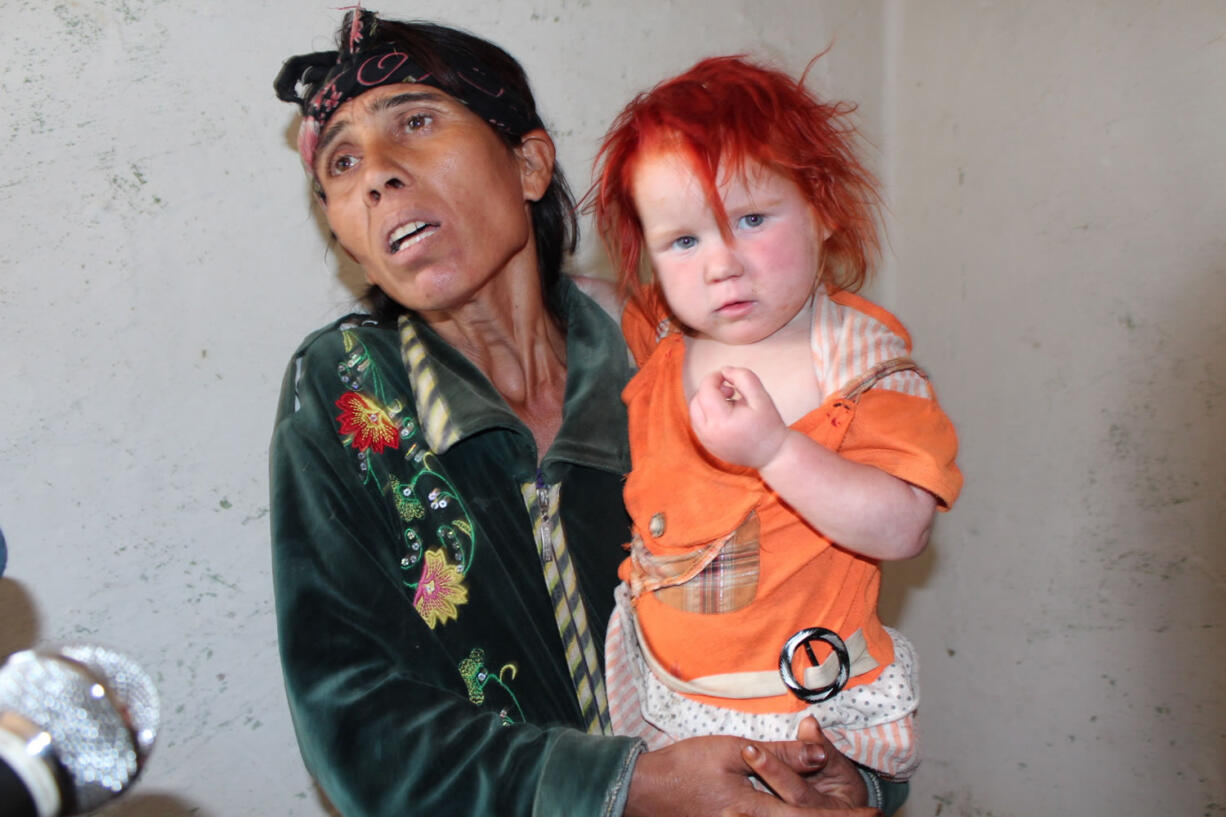 Sasha Ruseva holds 2-year-old Penka, one of her 10 children, whom she claims is albino, while she talks to journalists in the town of Nikolaevo , Bulgaria on Thursday. DNA tests have confirmed that Sasha Ruseva, 35, and her husband, Atanas, are the biological parents of Maria, a girl found in Greece with another Roma couple, Interior Ministry official Svetlozar Lazarov said Friday. Ruseva says she gave birth to a baby girl four years ago in Greece while working as an olive picker but gave the child away because she was too poor to care for her. She since has had two more children.