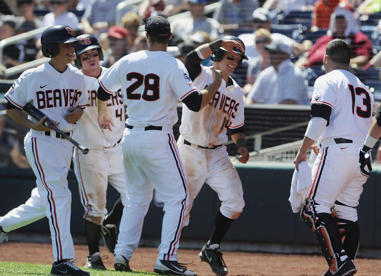 Oregon State's Max Gordon (4) and Andy Peterson (14) celebrate with teammates Ben Wetzler (28) and Jake Rodriguez (13) after they scored on a two-run single by Dylan Davis against Louisville in the fourth inning Monday.