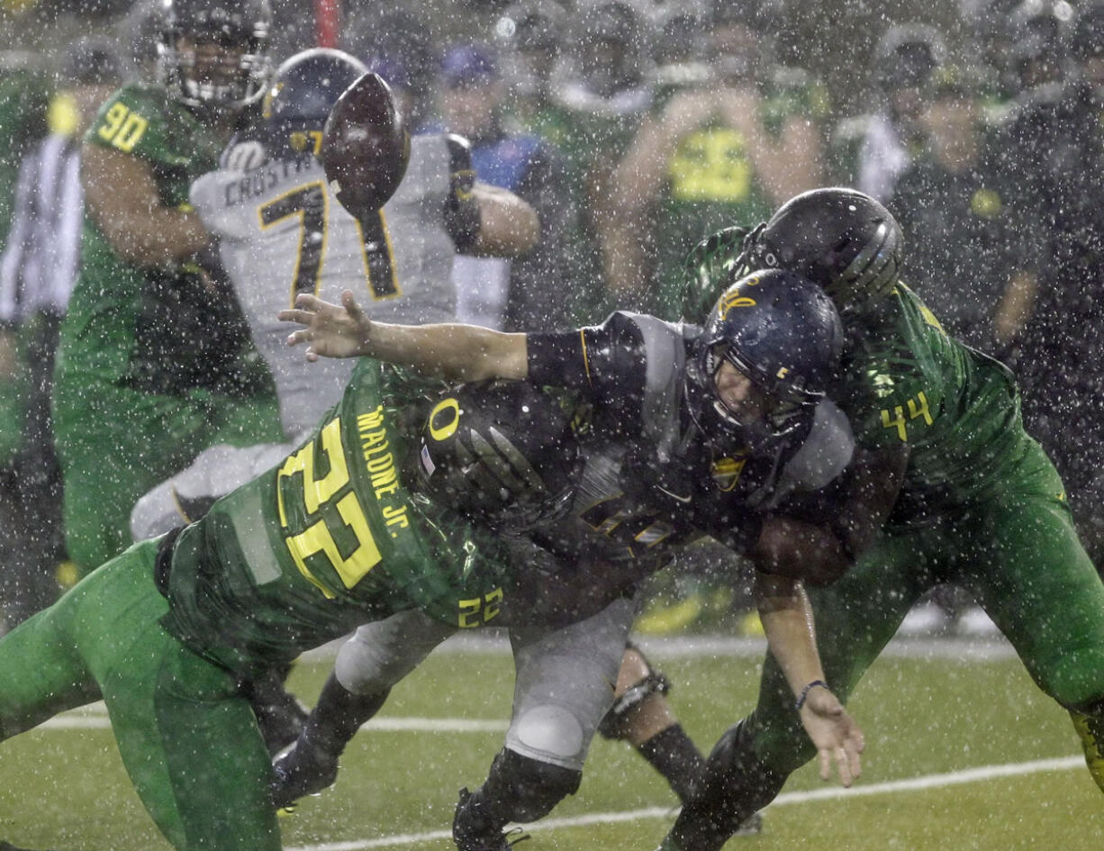 California quarterback Jared Goff, middle, fumbles the ball as he is tackled by Oregon defenders Derrick Malone Jr., left, and DeForest Buckner during the first half in the rain in Eugene.