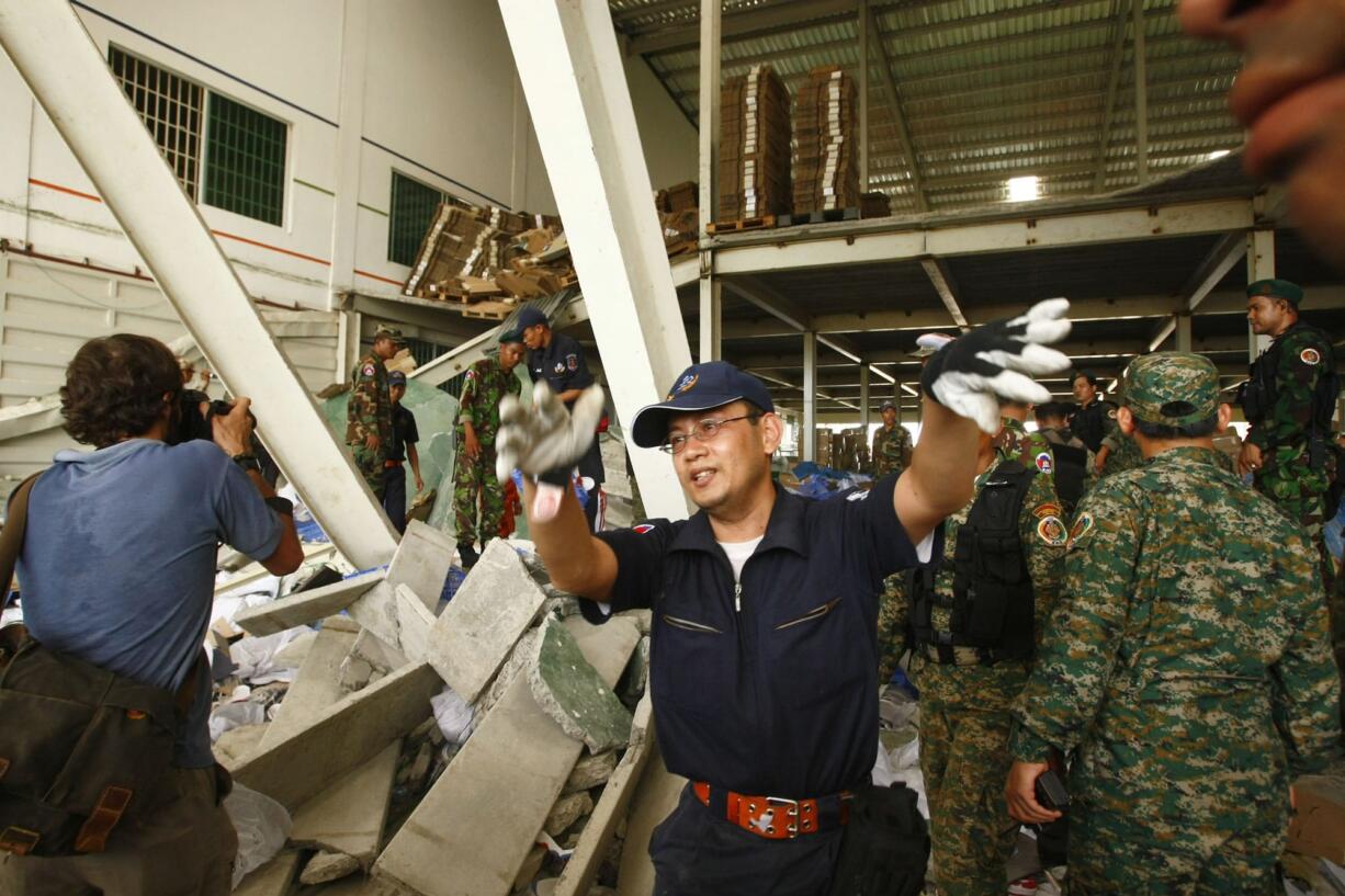 A Cambodian rescue officer, center, tries to clear watching people from the site of a factory collapse in Kai Ruong village, south of Phnom Penh, Cambodia, on Thursday.