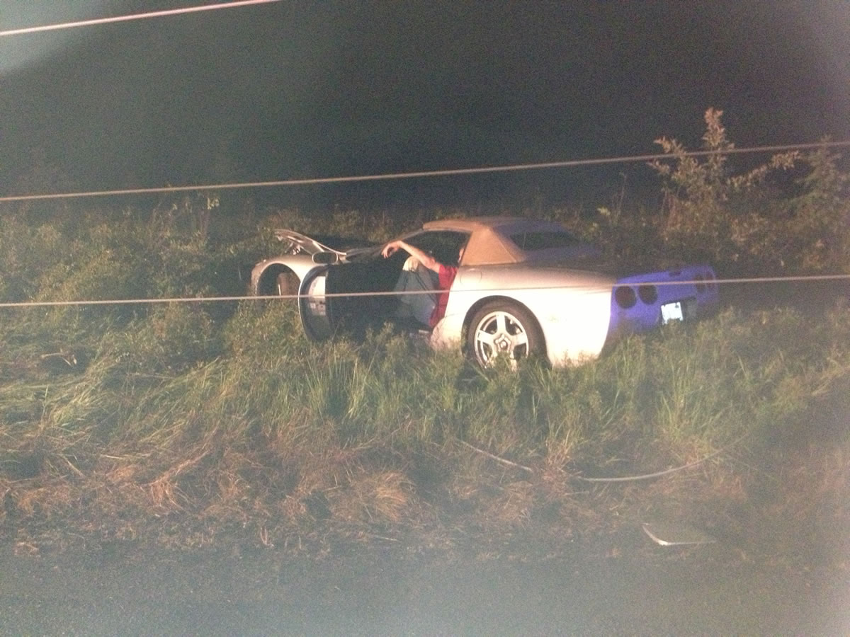 Ethan Cross of Battle Ground sits in the wreckage of his newly purchased Chevrolet Corvette as he waits for downed power lines to be made safe.