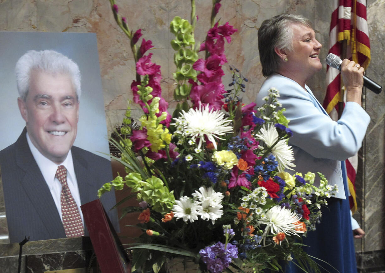 Rep. Maureen Walsh sings during a memorial service on the Senate floor for the late Sen. Mike Carrell, pictured left, on Monday in Olympia .