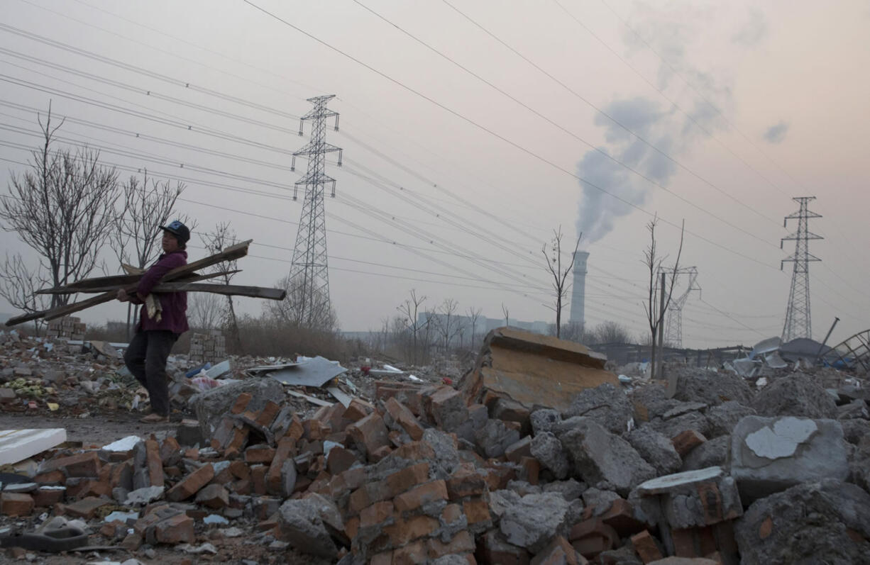 A scrap collector salvages material from a demolished neighborhood near a chimney spewing smoke, in Beijing, China. China&#039;s push for a global climate pact was partly because of its own increasingly pressing need to solve serious environmental problems, observers said Sunday.