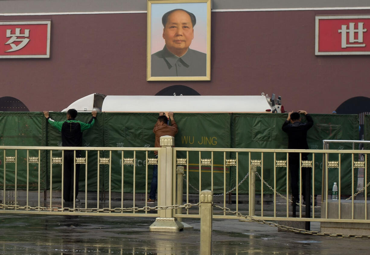 Chinese plainclothes policemen place green net shields in front of Tiananmen Gate following a car fire in Beijing on Monday.