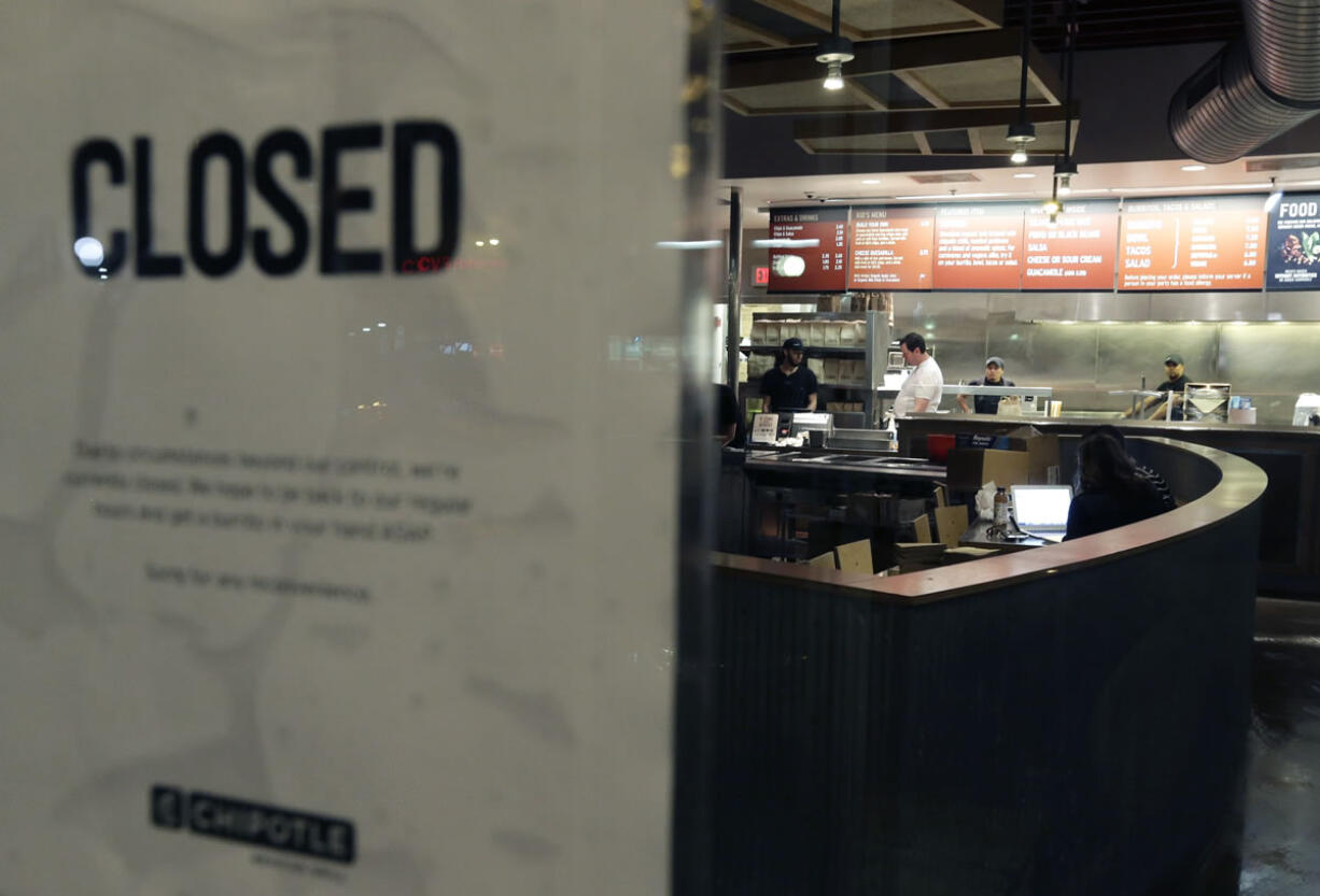 People stand inside a closed Chipotle restaurant on Monday in the Cleveland Circle neighborhood of Boston. Chipotle said late Monday that it closed the restaurant after several students at Boston College, including members of the men&#039;s basketball team, reported &quot;gastrointestinal symptoms&quot; after eating at the chain. The school said it was working with local health officials to determine the cause of the illness.