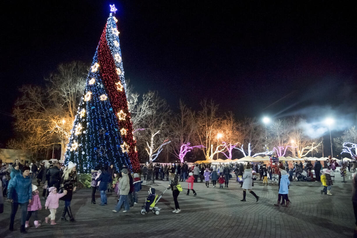 People walk at Nakhimov&#039;s Square in Sevastopol, Crimea. As New Year&#039;s Eve approaches, the central square of Crimea?s largest city is festooned with lighted holiday decorations, including a soaring artificial tree that flashes and winks. But areas a few steps away are sunk in darkness, the streetlamps turned off because of an electricity shortage.