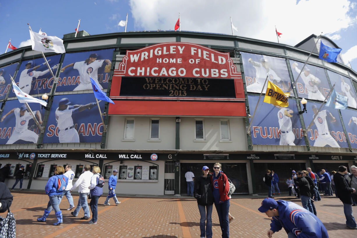 People walk outside Wrigley Field in Chicago before the Chicago Cubs 2013 season home opening baseball game against the Milwaukee Brewers.