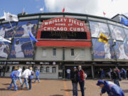 People walk outside Wrigley Field in Chicago before the Chicago Cubs 2013 season home opening baseball game against the Milwaukee Brewers.