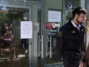 A private security services guard, right, stands in front of the bank's main door as people wait outside a branch of Laiki Bank in Nicosia on March 28.