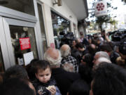 People wait outside a branch of Laiki Bank in Nicosia on Thursday.