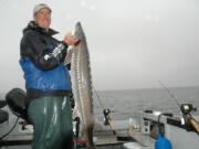 Guide Bob Rees holds a sturgeon caught in early June near the Port of Hammond at the mouth of the Columbia River.