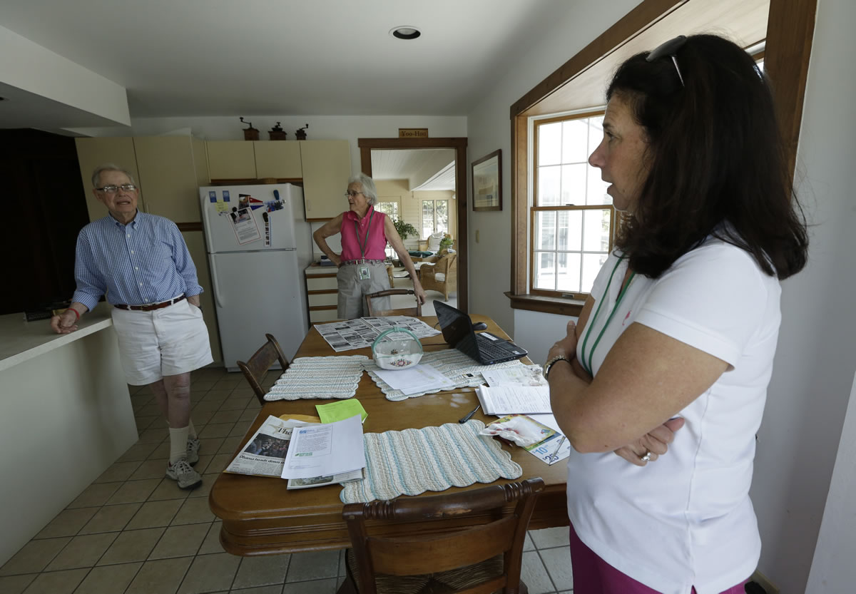 In this Friday, May 31, 2013 photo, Robert Post, left, and his wife, Jane Post, center, talk to neighbor Gail Kender inside their home, in Mantoloking, N.J., which was flooded during Superstorm Sandy last year. Robert Post, 85, has a pacemaker that needs to be checked once a month by phone, but the phone company refuses to restore the area's landlines after they were damaged by the storm. Verizon doesnit want to replace washed-away lines and waterlogged underground cables because phone lines are outdated, it says. Meanwhile, the company is offering a wireless device that can be plugged into home phones for service, but the system does not work with pacemakers or fax machines.