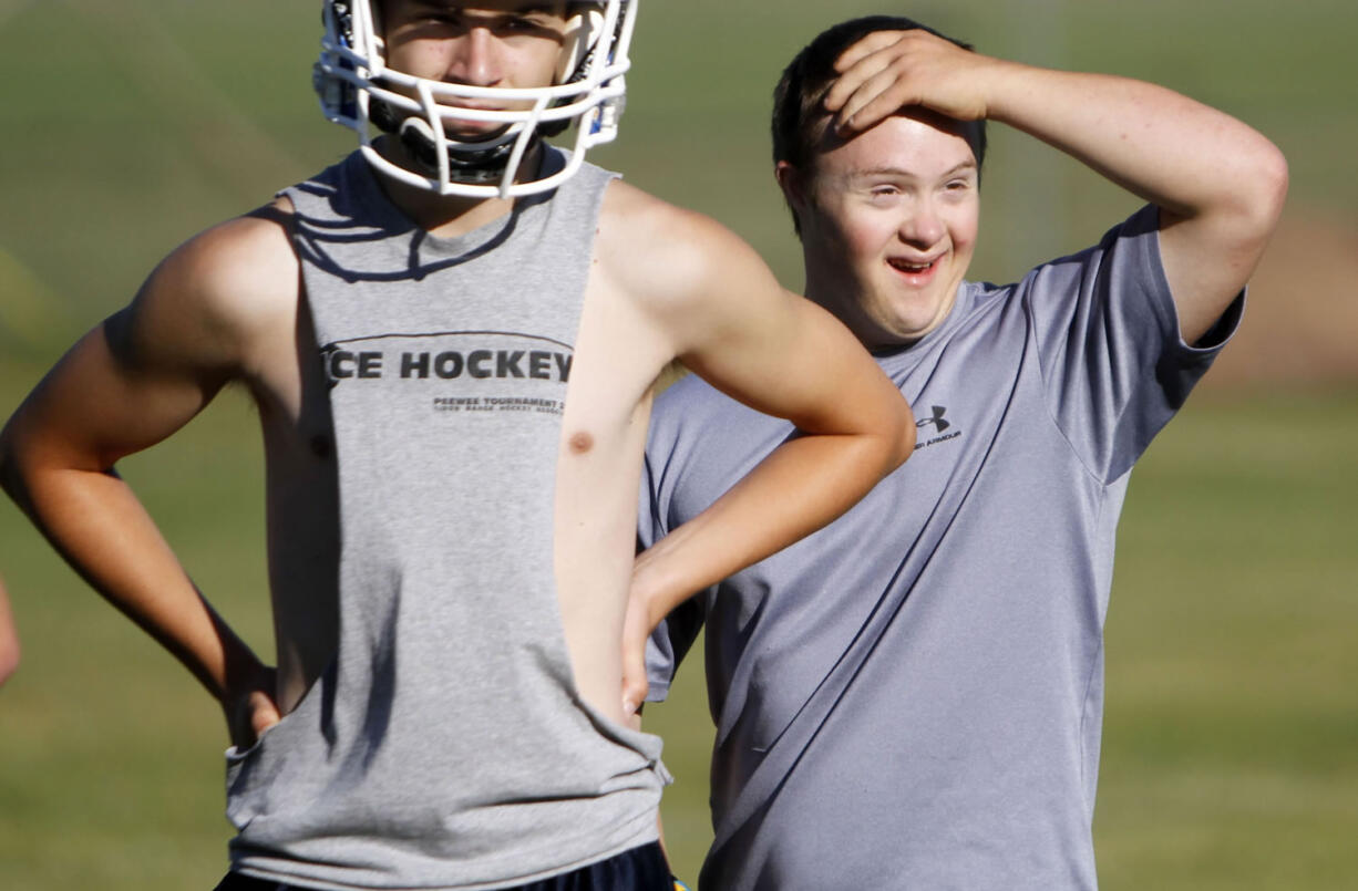 Eric Dompierre, 19, right, who has Down syndrome and is the kicker for the Ishpeming High School varsity football team, arrives on the field for the first day of practice at the Ishpeming Playgrounds in Ishpeming, Mich. on Aug. 6, 2012. Breaking new ground, the U.S. Education Department is telling schools Friday, Jan. 25, 2013, they must include students with disabilities in sports programs or provide equal alternative options.