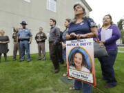 Carol Jones-Blair, second from right, holds a poster of her daughter Sheena Blair, who was killed in an accident with a wrong-way driver in 2010, as she attends a bill-signing ceremony Thursday in Tacoma. Washington Gov.